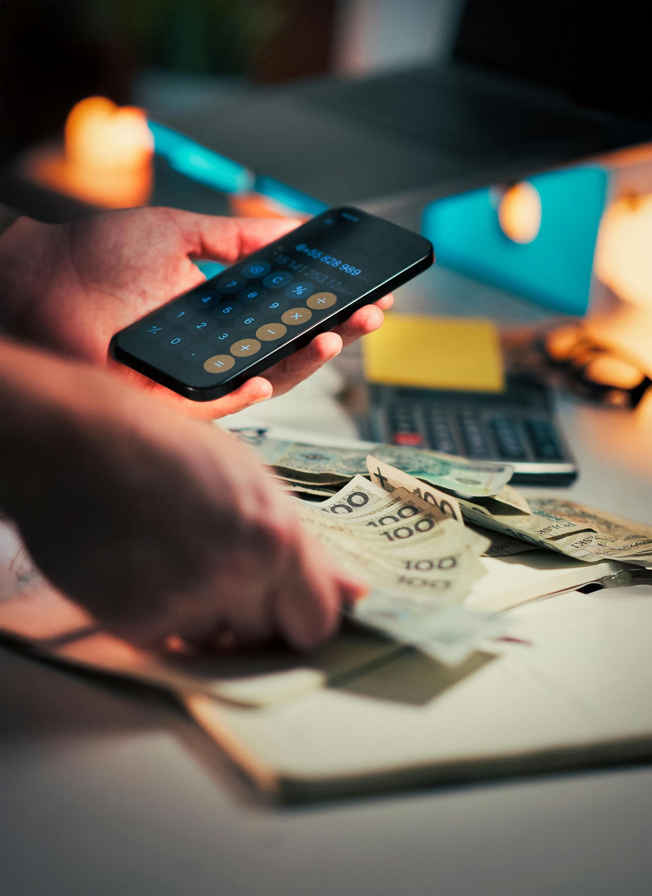 Persona calculando gastos y comisiones bancarias con móvil y efectivo