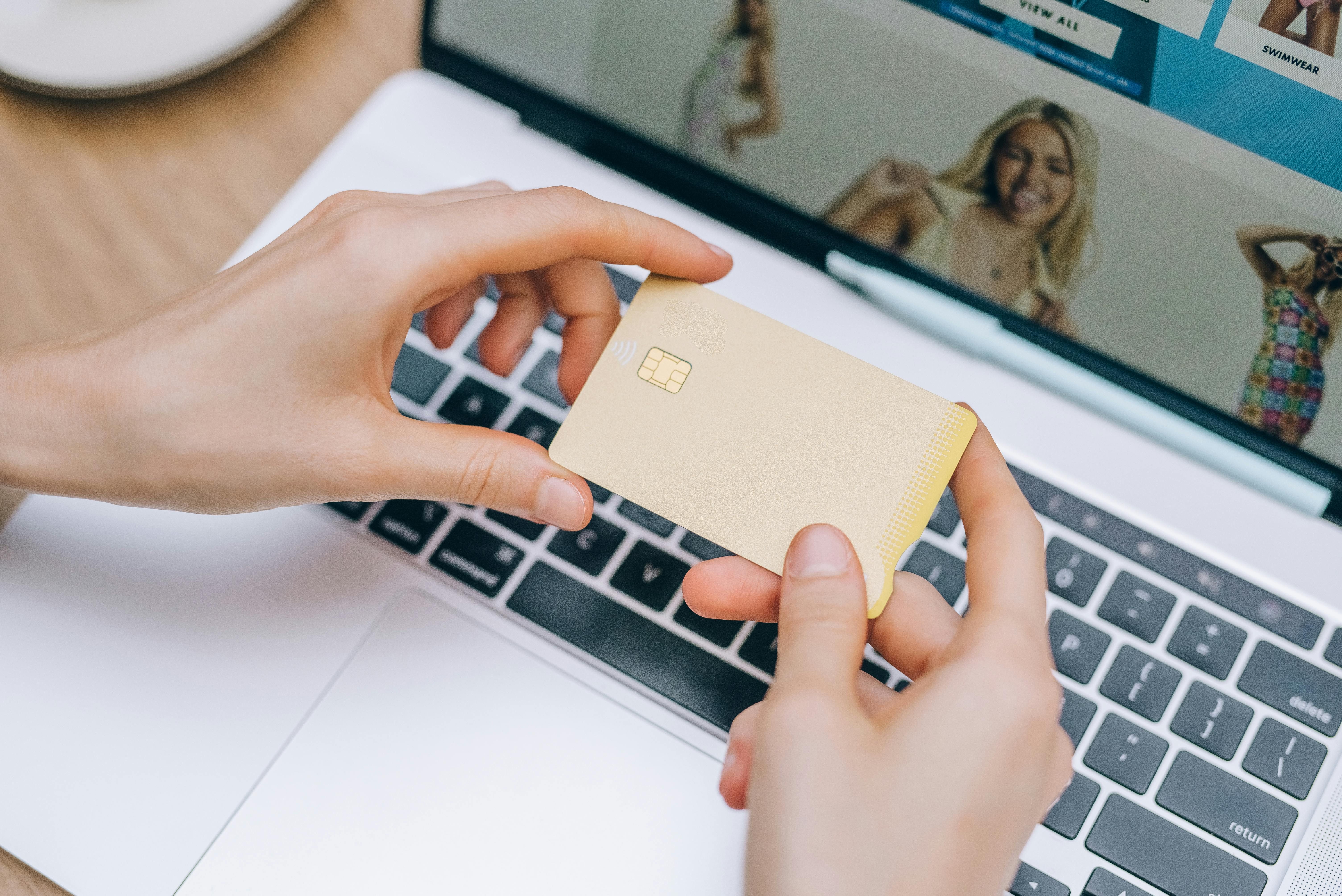 Persona comparando cuentas bancarias online con tarjeta y portátil